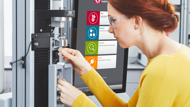Female lab operator in safety glasses carefully loading a syringe into a syringe testing fixture on an Instron universal testing machine, with the Instron Bluehill Universal interface displaying test, method, analysis, and admin menu options in the background | Instron